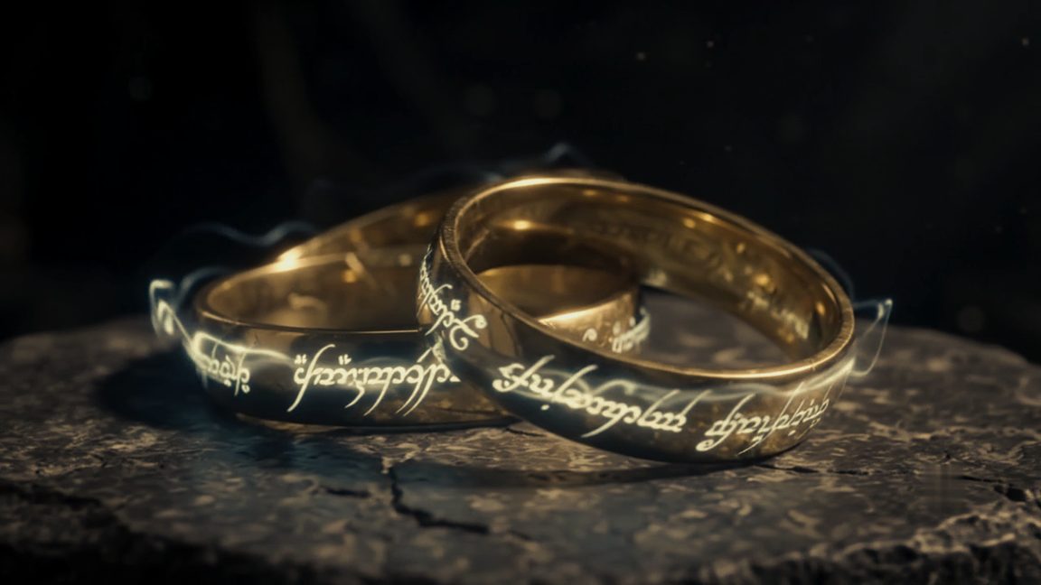 Their two wedding bands on stone, gold, each carrying an inscription that catches the light.